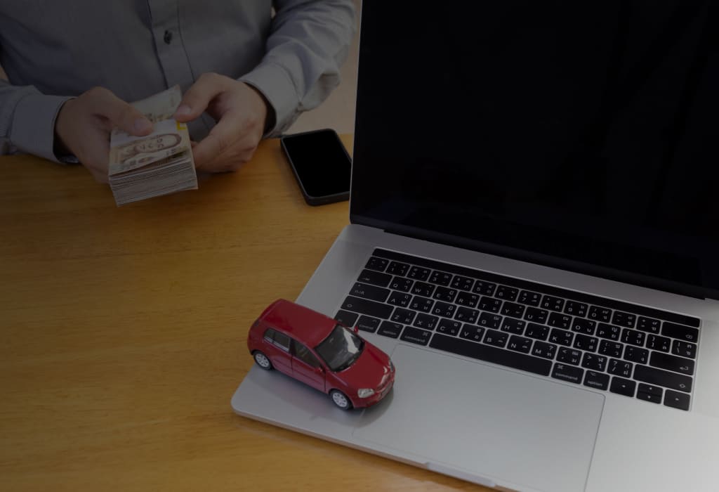 человек держит деньги перед ноутбуком с машинкой