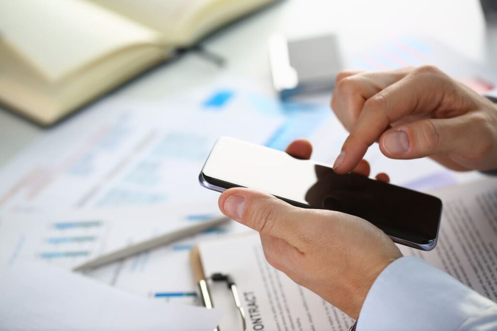 человек держит телефон на фоне документов