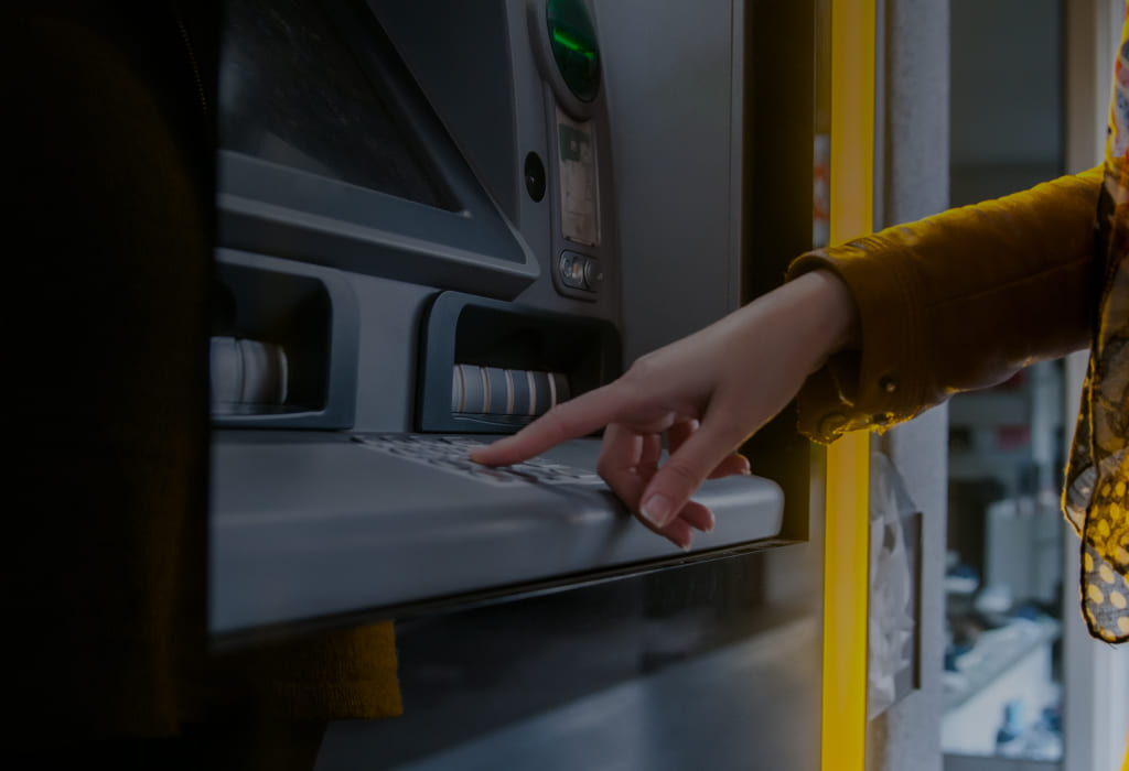 Человек набирает пин в банкомате