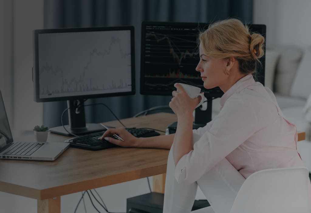 девушка сидит напротив мониторов с графиками