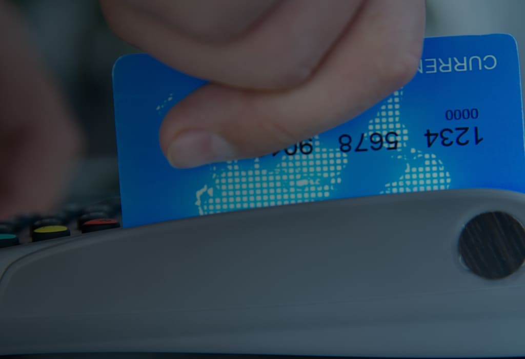 человек проводит картой по эквайринговому аппарату  