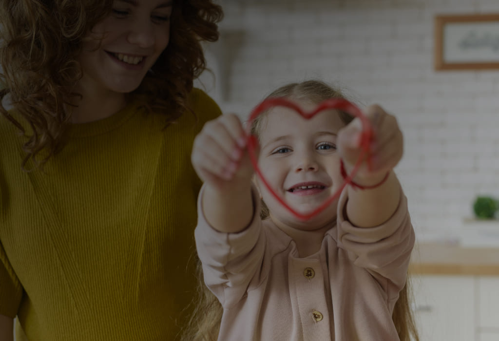 Ребёнок рядом с мамой показывает сердечко