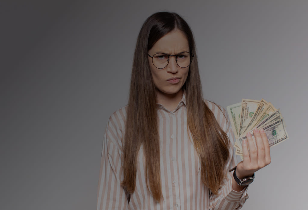 недовольная девушка держит деньги