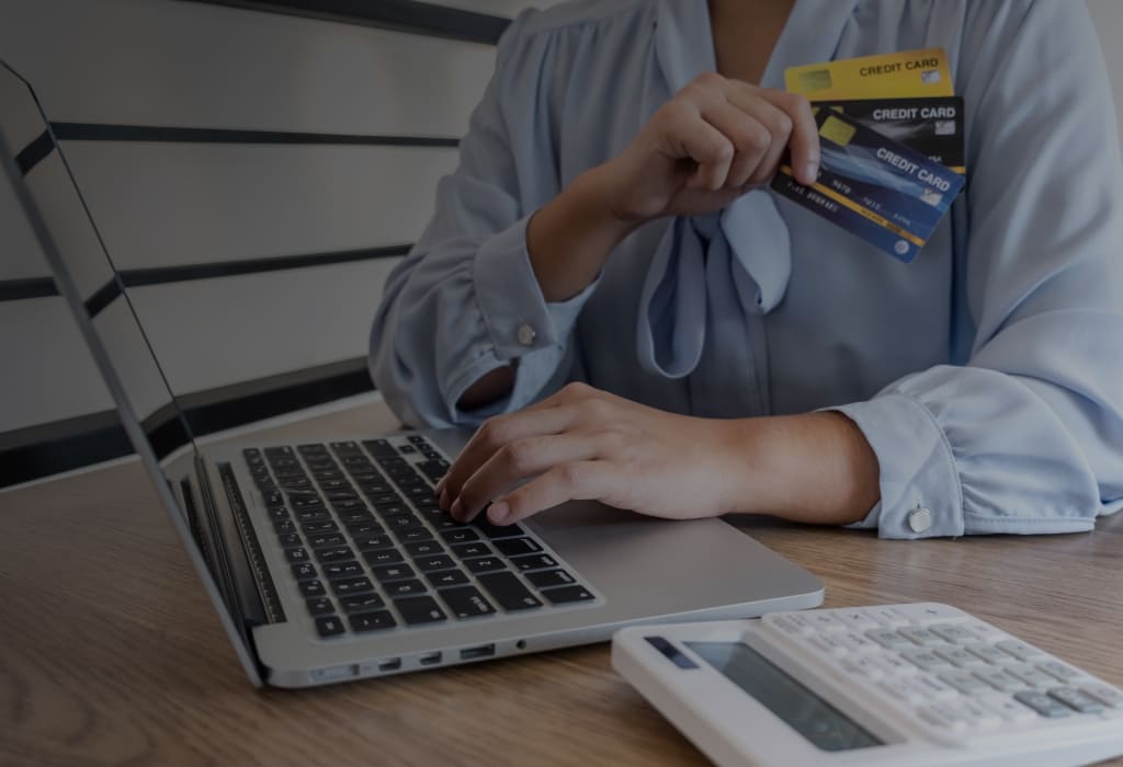 Деловая женщина использует ноутбук и держит в руках кредитную карту.